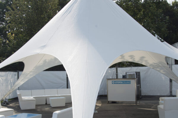 A modern event tent with a unique sail-shaped roof, offering a stylish design for outdoor events, with a clean white fabric and spacious seating area inside.